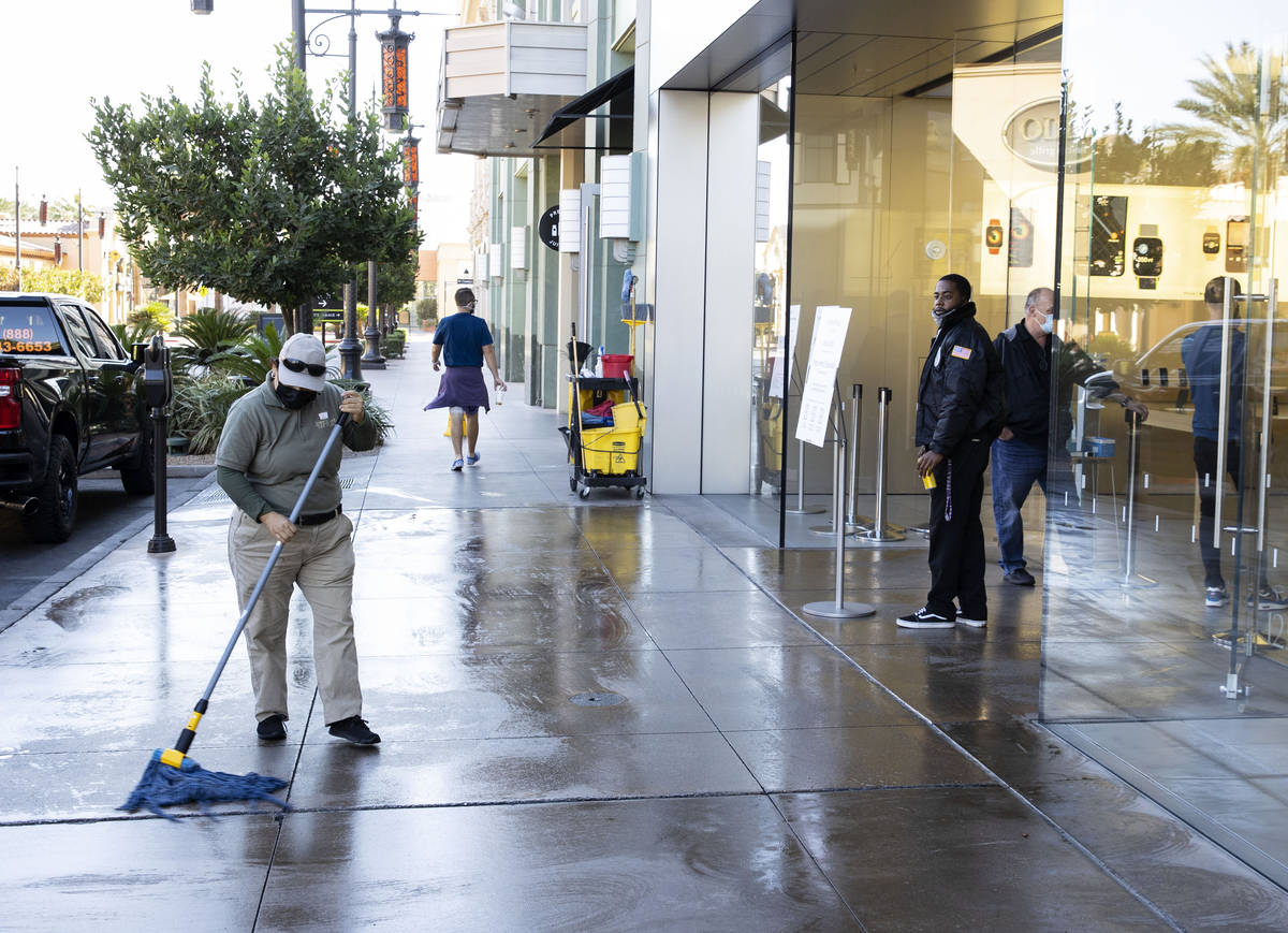 A worker mops a sidewalk outside of an Apple store after an electrical malfunction caused a fir ...