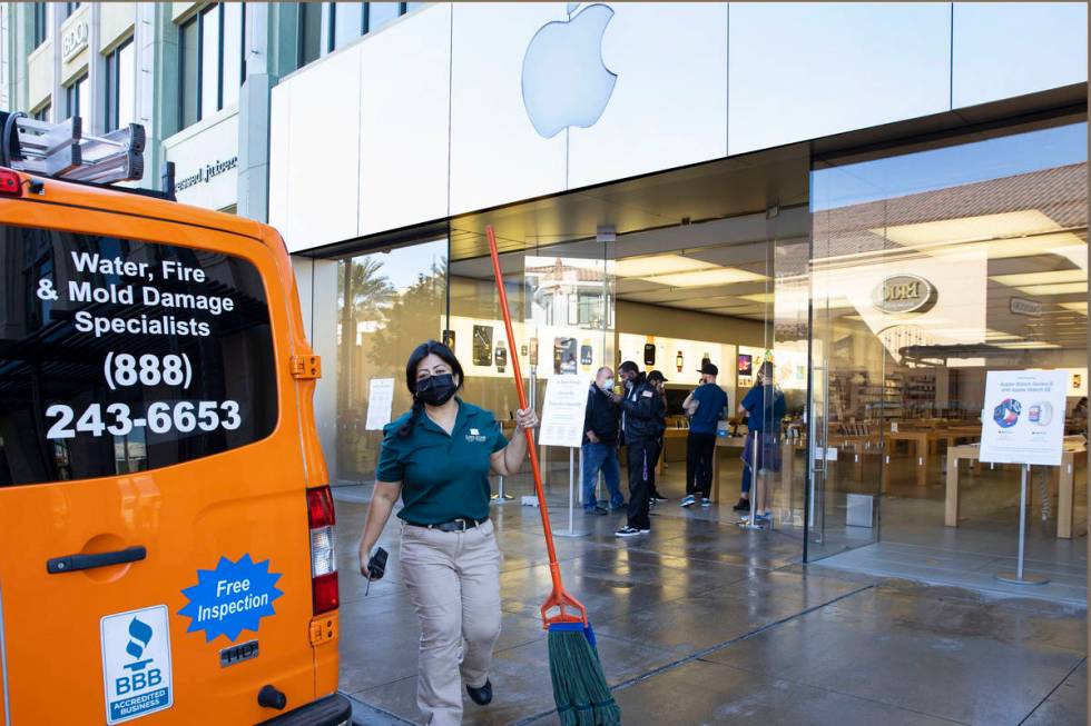 A worker mops a sidewalk outside of an Apple store after an electrical malfunction caused a fir ...