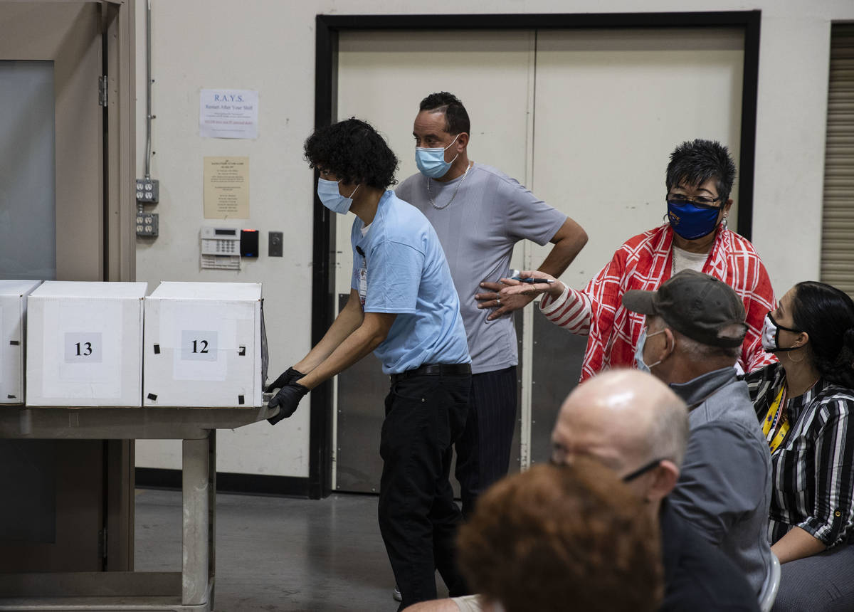 Election observers, right, watch as Clark County election workers deliver ballots to be counted ...