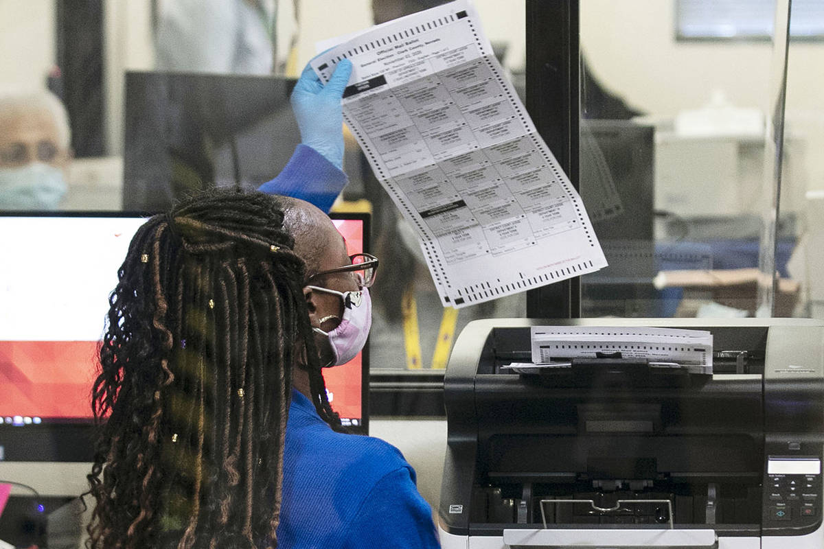 A Clark County election worker checks out a ballot as she prepares to scan it at the Election D ...