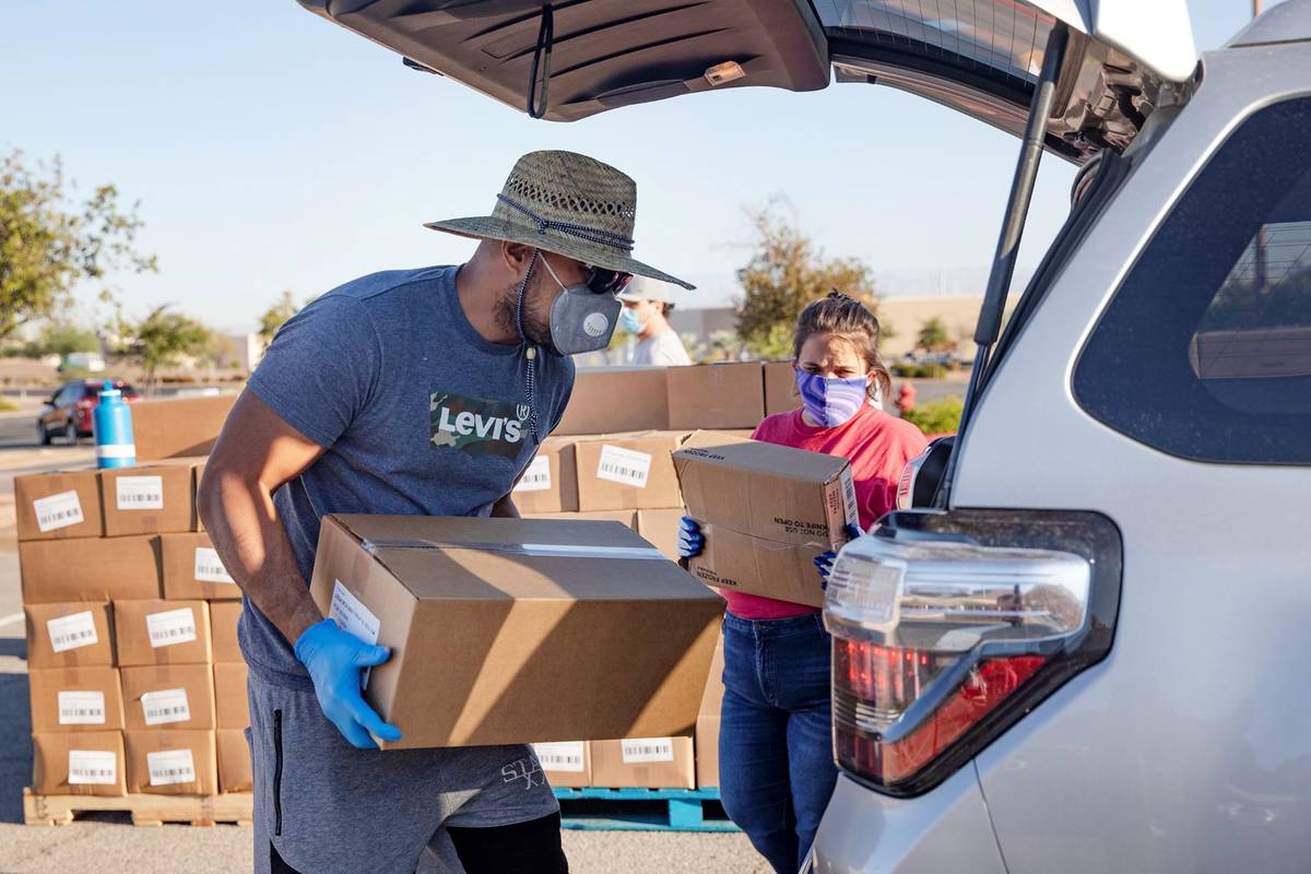 Volunteer Leonid Tuiasosopo, left, and Nicole McKinney, right, place food in the back of a pers ...