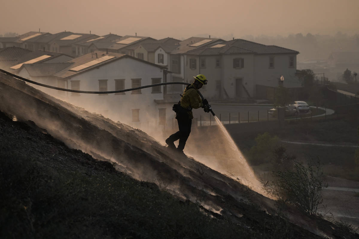 Firefighter Tylor Gilbert puts out hotspots while battling the Silverado Fire, Monday, Oct. 26, ...