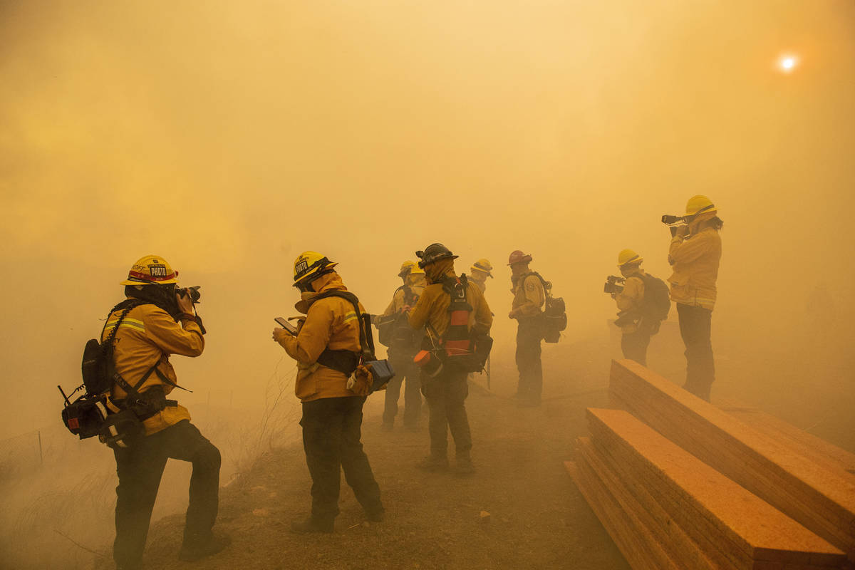 Firefighters with Cal Fire are enveloped in smoke as fire from the Green Fire passes by near ho ...