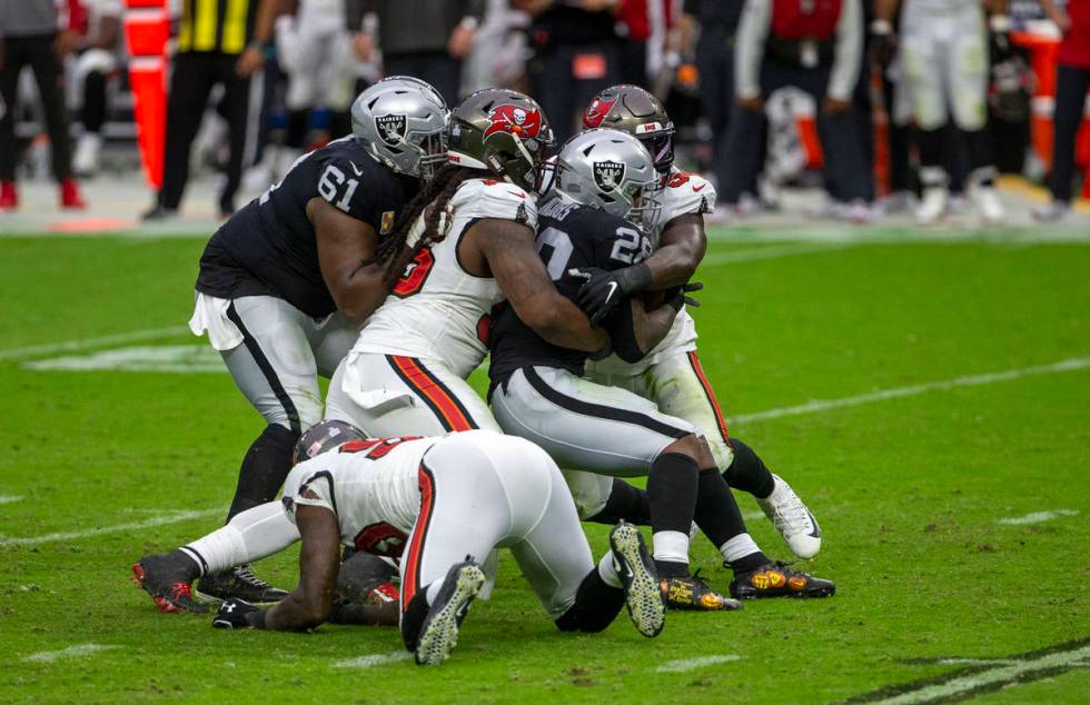 Las Vegas Raiders center Rodney Hudson (61) tries to assist as running back Josh Jacobs (28) is ...