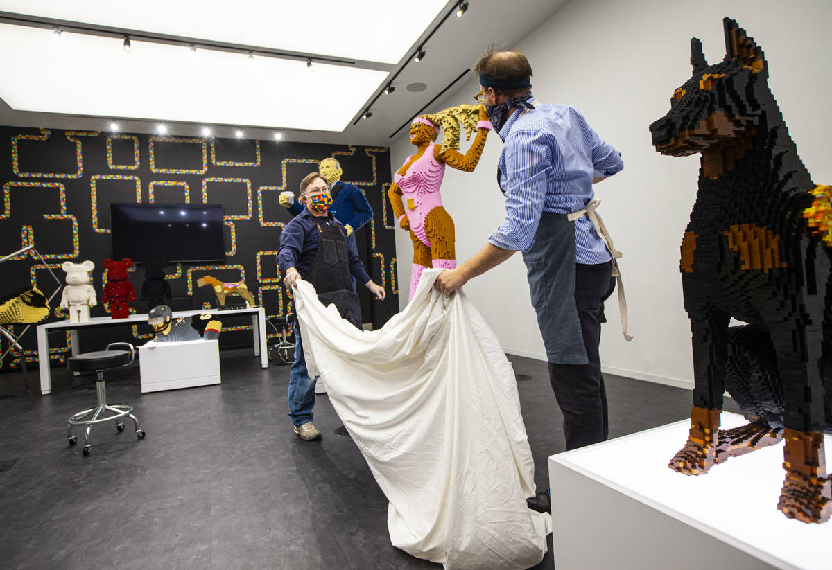 Artist Chris Ihle, right, and lead builder Doug Kinney, left, unveil a custom LEGO statue of Sa ...