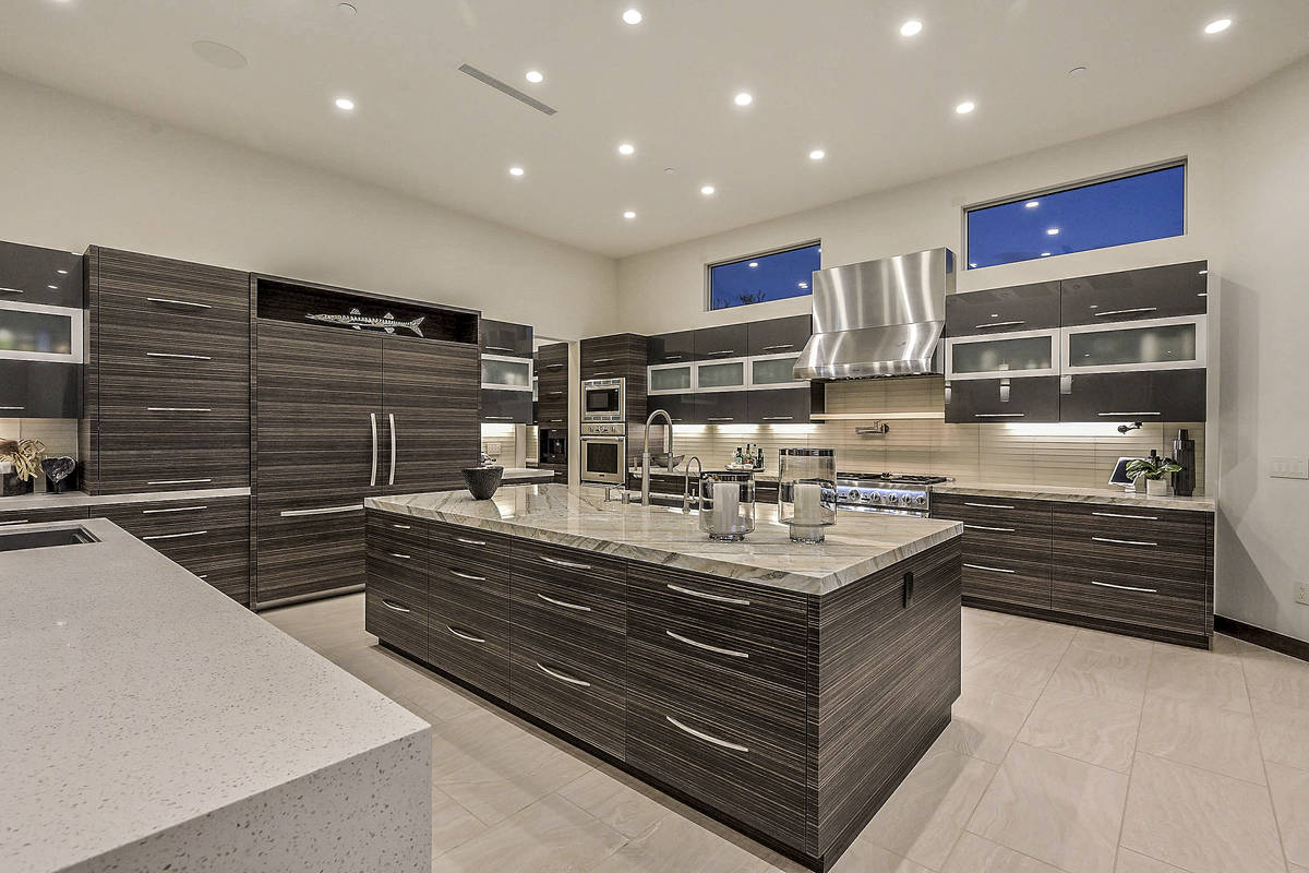 The kitchen features plenty of custom cabinets, Brazilian quartzite waterfall counters and a la ...
