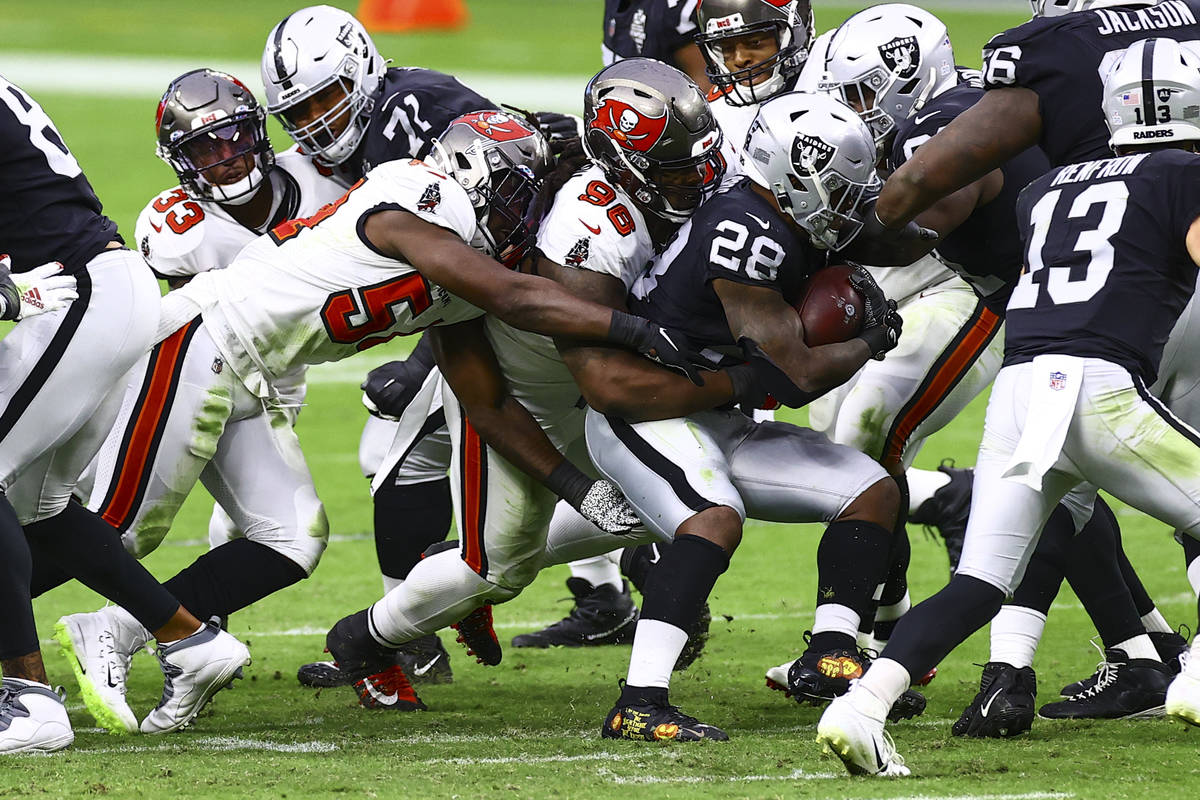 Las Vegas Raiders running back Josh Jacobs (28) gets stopped by Tampa Bay Buccaneers defensive ...