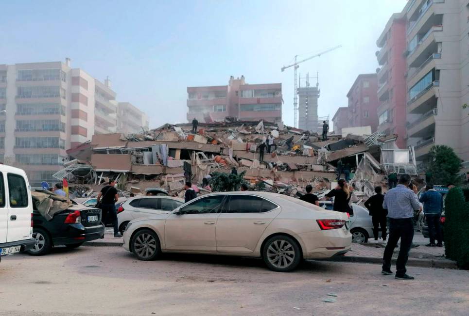 People work on a collapsed building, in Izmir, Turkey, Friday, Oct. 30, 2020, after a strong ea ...