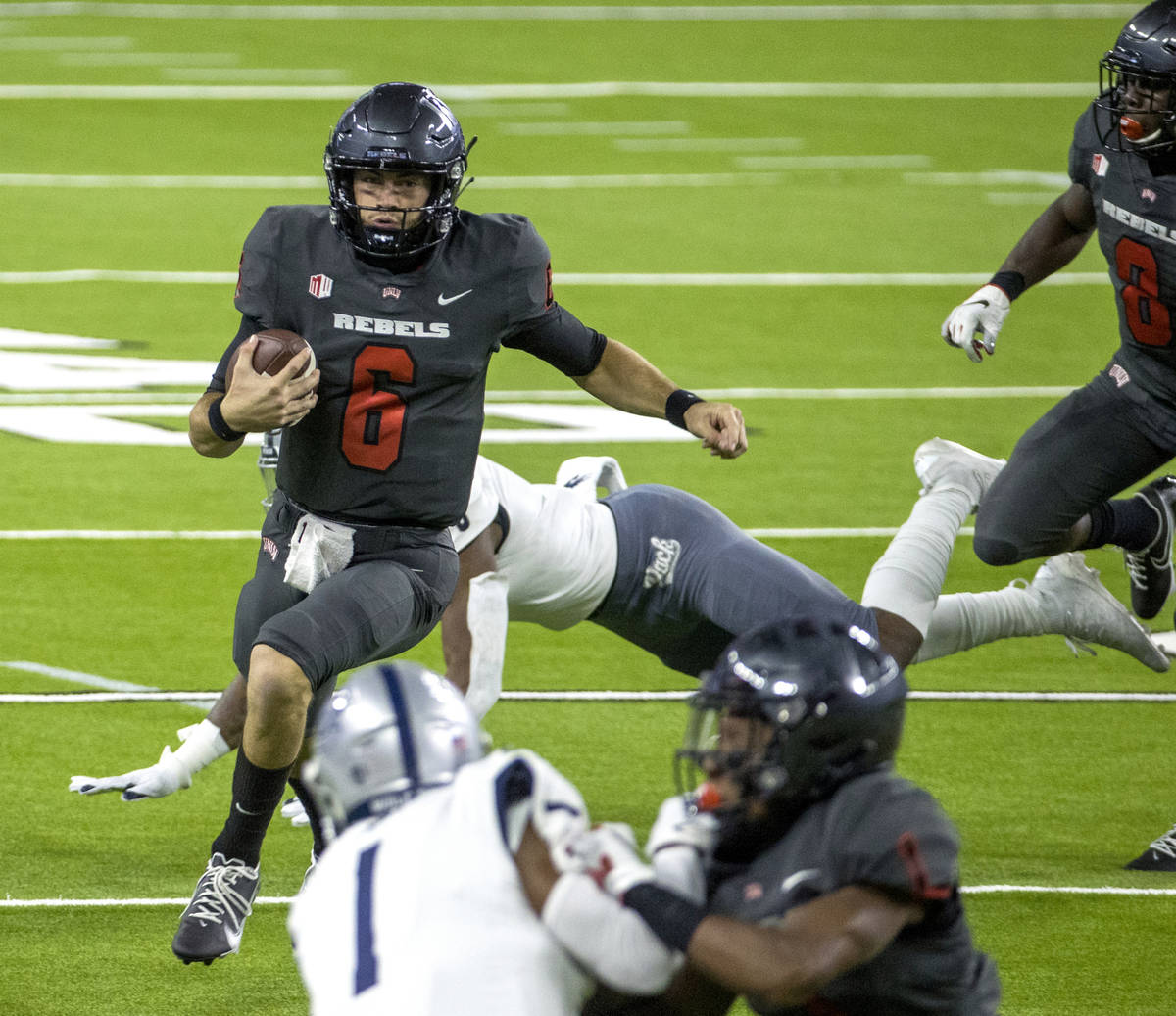 UNLV Rebels quarterback Max Gilliam (6) turns the corner field past a diving Nevada Wolf Pack d ...