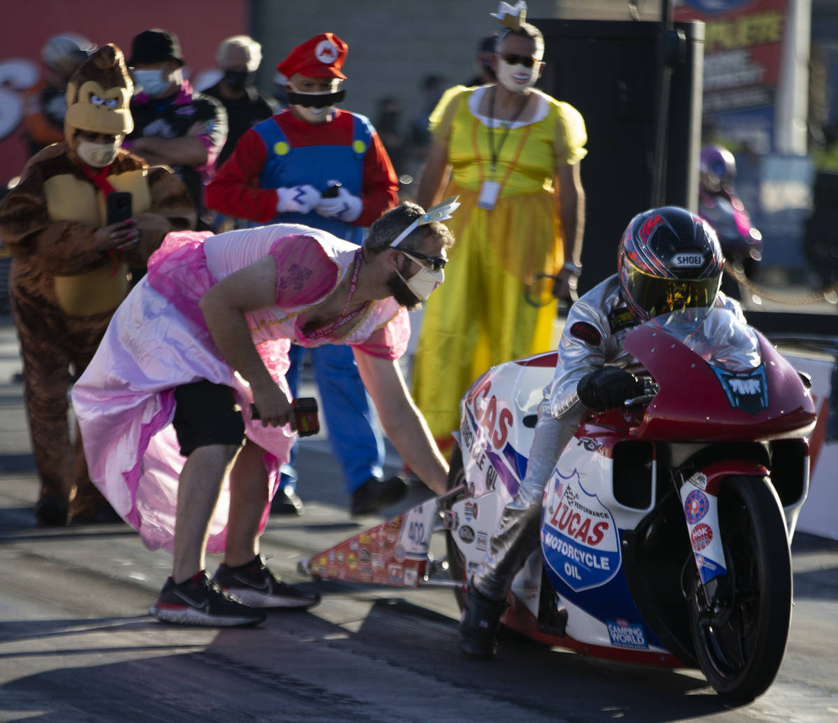 Crew members wear Halloween costumes as Pro Stock driver David Barron gets ready to race during ...