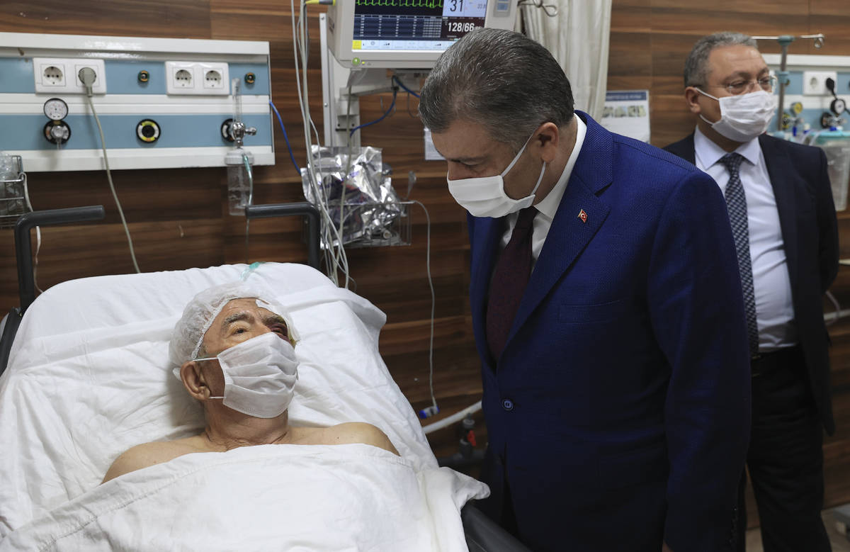 Turkey's Health Minister Fahrettin Koca speaks with Ahmet Citim, rescued from the debris of his ...