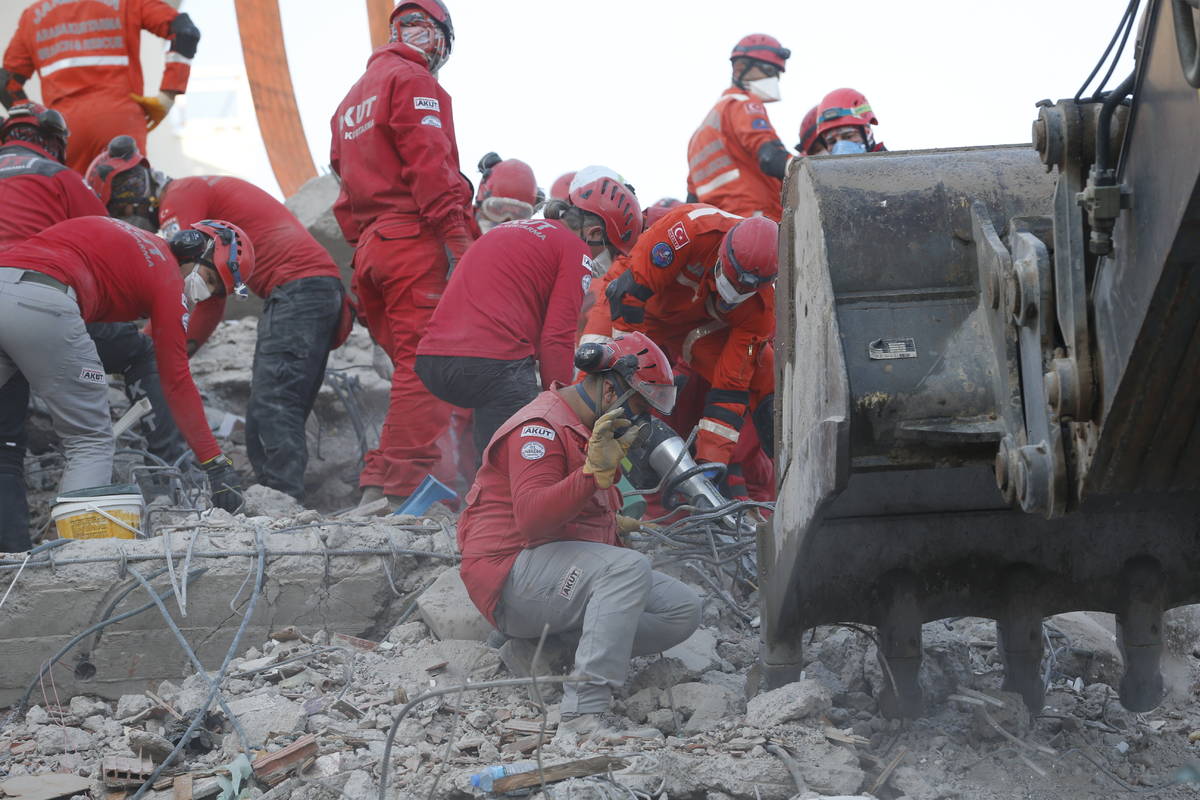 Members of rescue services search in the debris of a collapsed building for survivors in Izmir, ...