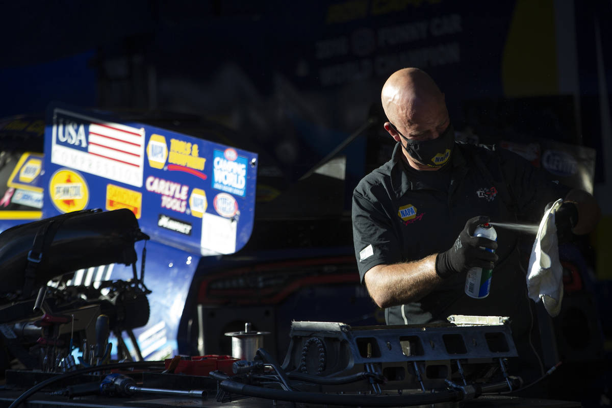 A member of Funny Car driver Ron Capps' crew services the team's car during the Dodge NHRA Fina ...