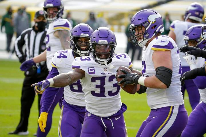 Minnesota Vikings' Ezra Cleveland (72) helps Dalvin Cook (33) celebrate his touchdown run durin ...