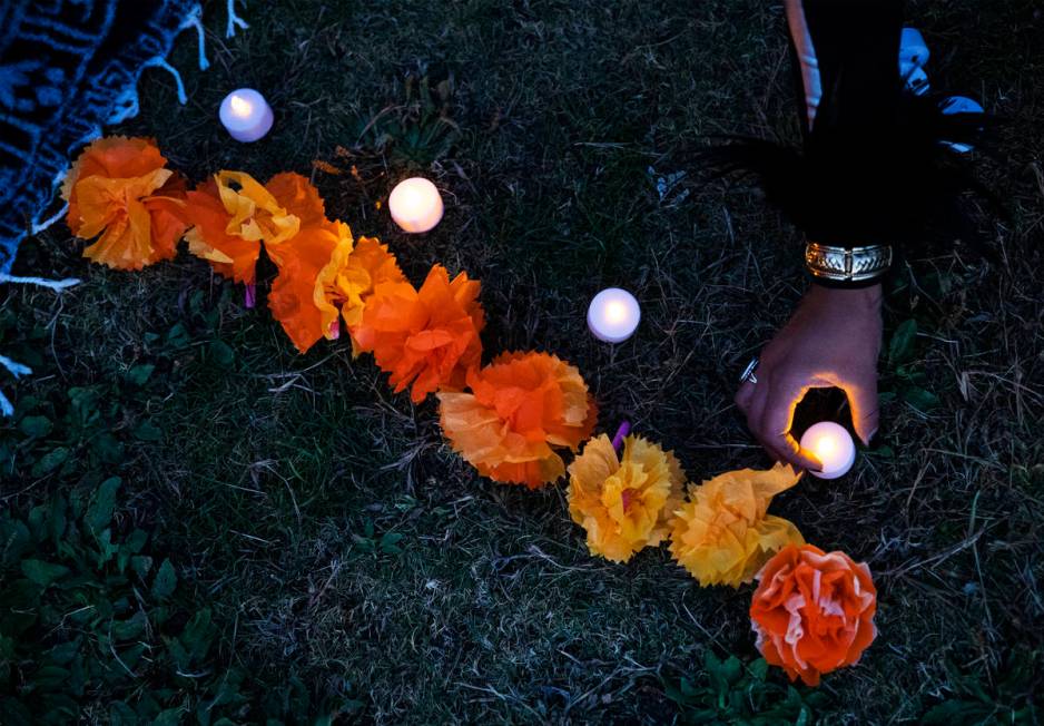 Ingrid ollintzihuatl Moctezuma sets out a candle at a Día de los Muertos event to honor pe ...