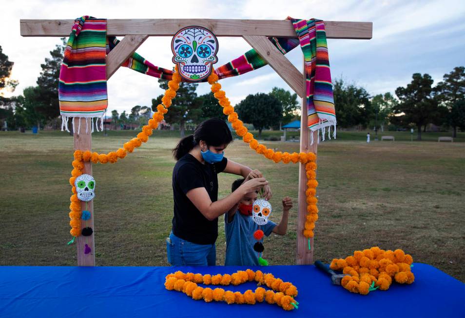 Ana Medina hangs a skull decoration with her son Freddy Medina, 6, at a Día de los Muertos ...