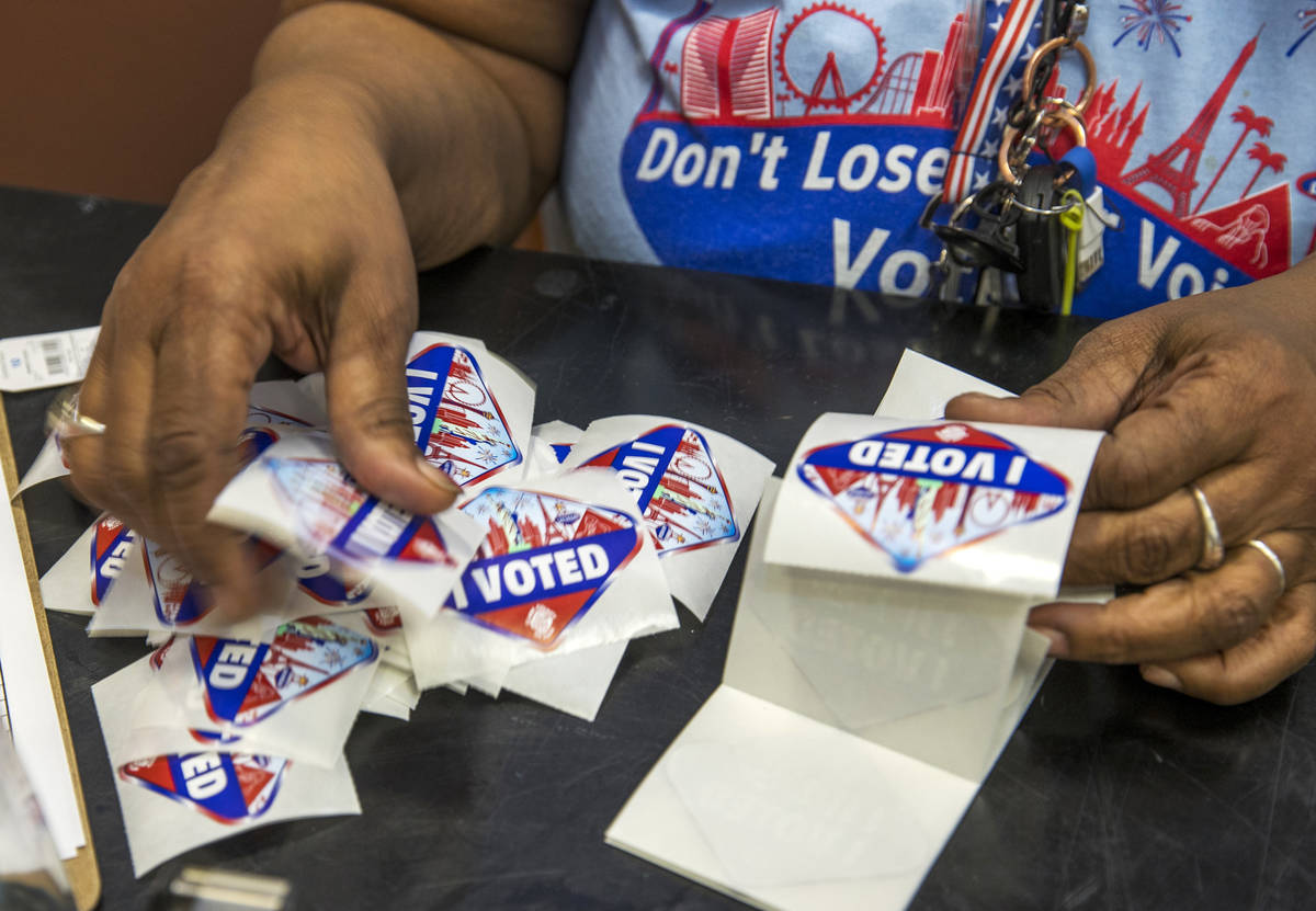 Elections worker Robin Wright readies "I Voted" stickers for mail-in ballot drop off voters dur ...