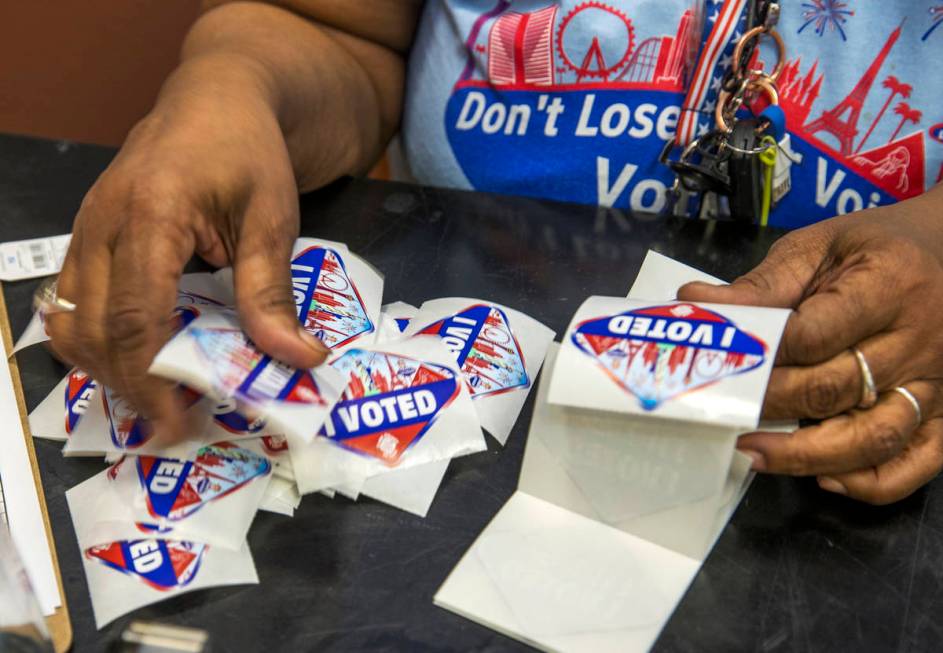 Elections worker Robin Wright readies "I Voted" stickers for mail-in ballot drop off voters dur ...