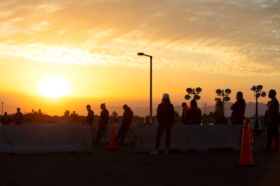 The sun rises behind voters as they wait in line nearly an hour before the voting site at Las V ...