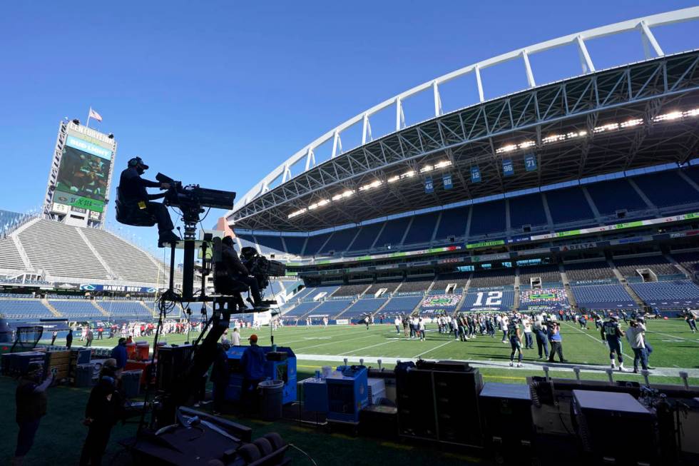 Two TV cameras mounted on a moving cart stand ready to capture action before an NFL football ga ...