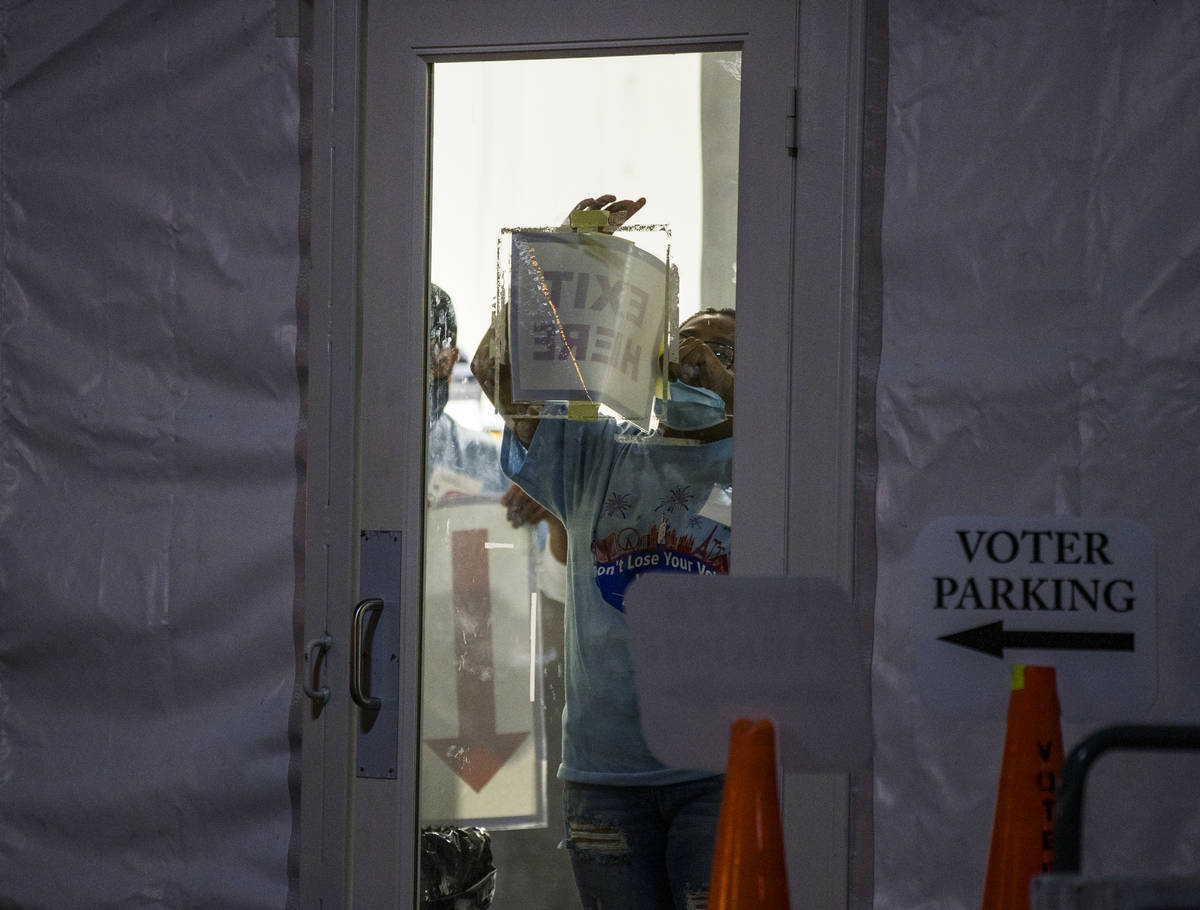 A worker removes the exit sign at the LVAC Rainbow voter center during Election Day on Tuesday, ...
