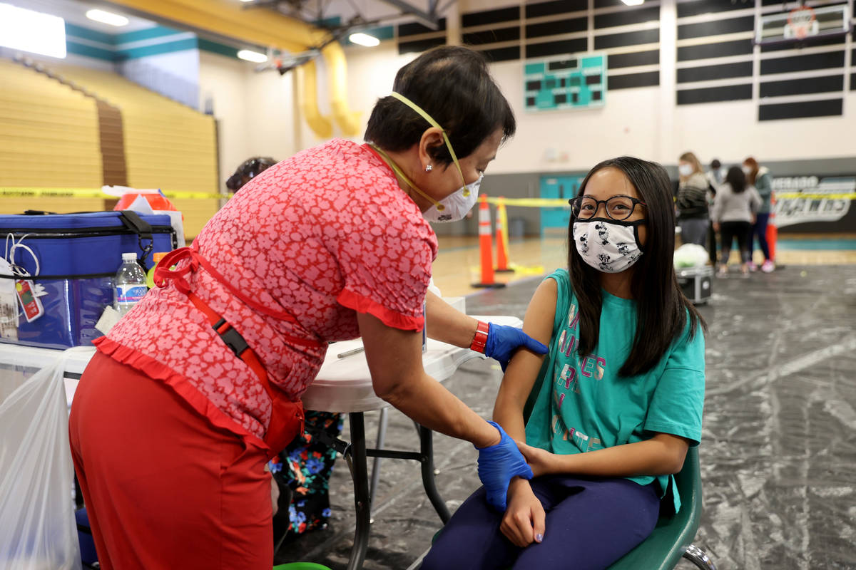 Megan Valdecantos, 10, of Henderson, gets a flu vaccine from Mila R., who declined to give her ...