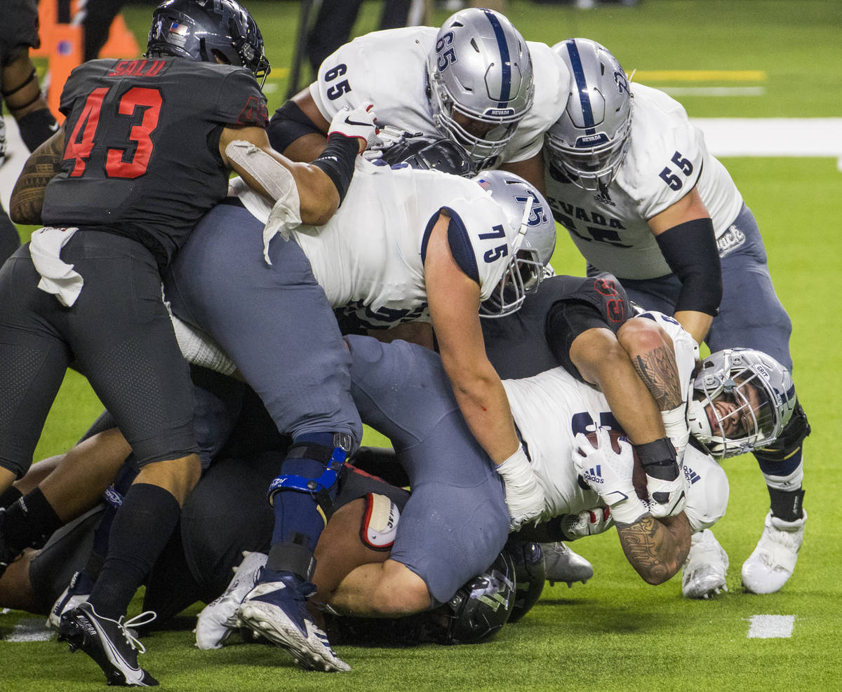 Nevada Wolf Pack running back Toa Taua (35, right) is taken down by the UNLV Rebels defense jus ...