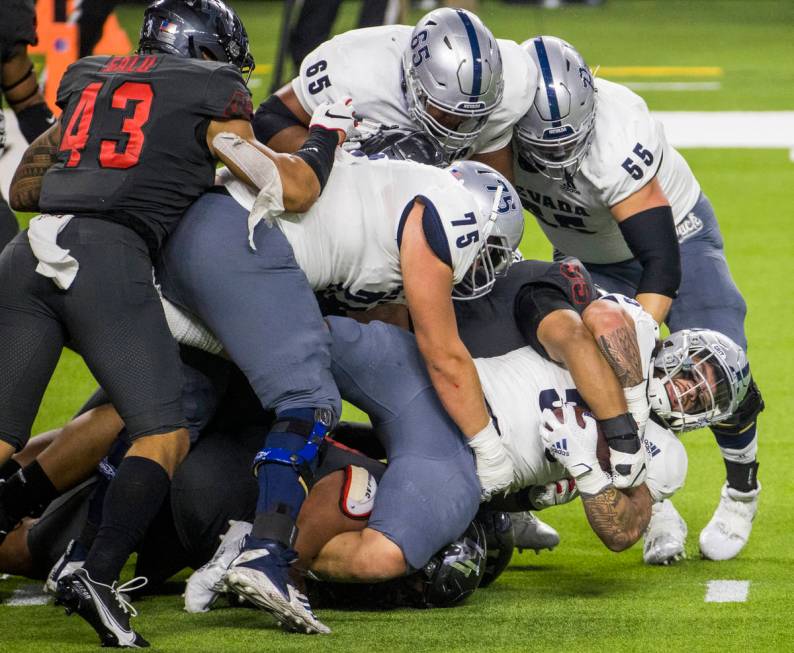Nevada Wolf Pack running back Toa Taua (35, right) is taken down by the UNLV Rebels defense jus ...