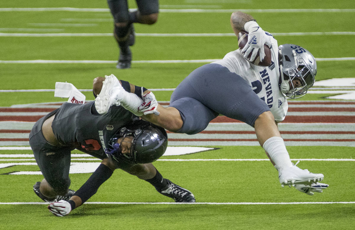 Nevada Wolf Pack running back Toa Taua (35) is taken down by UNLV Rebels defensive back Dominic ...