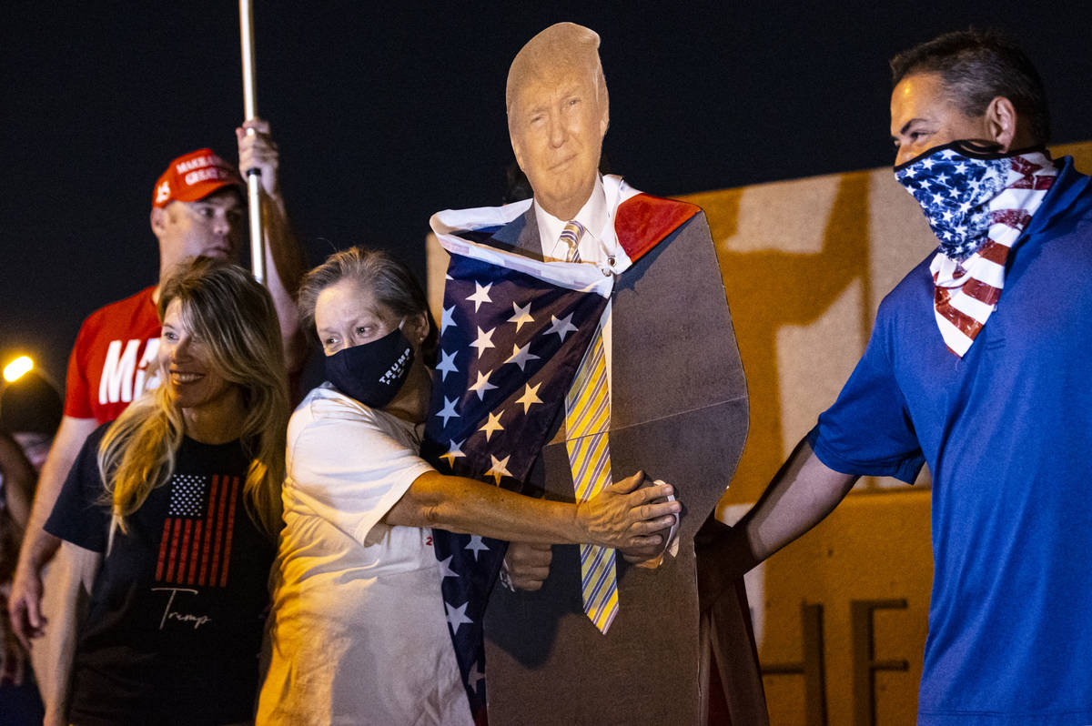 Supporters of President Donald Trump stand by a cardboard cutout of him while protesting outsid ...