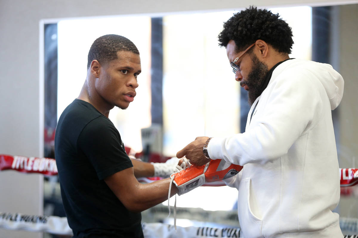 Boxer Devin Haney, left, puts on the gloves with the help of his father and trainer William &qu ...