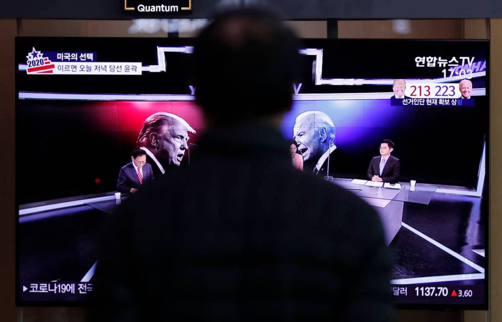 A man watches a TV screen showing the images of U.S. President Donald Trump and Democratic pres ...
