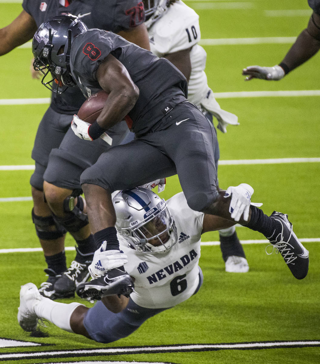 UNLV Rebels running back Charles Williams (8, top) is grabbed from below by a diving Nevada Wol ...