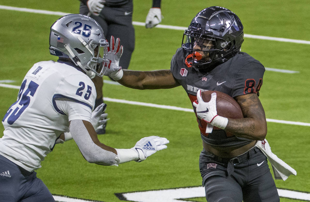 UNLV Rebels wide receiver Steve Jenkins (84, right) stiff arms Nevada Wolf Pack defensive back ...