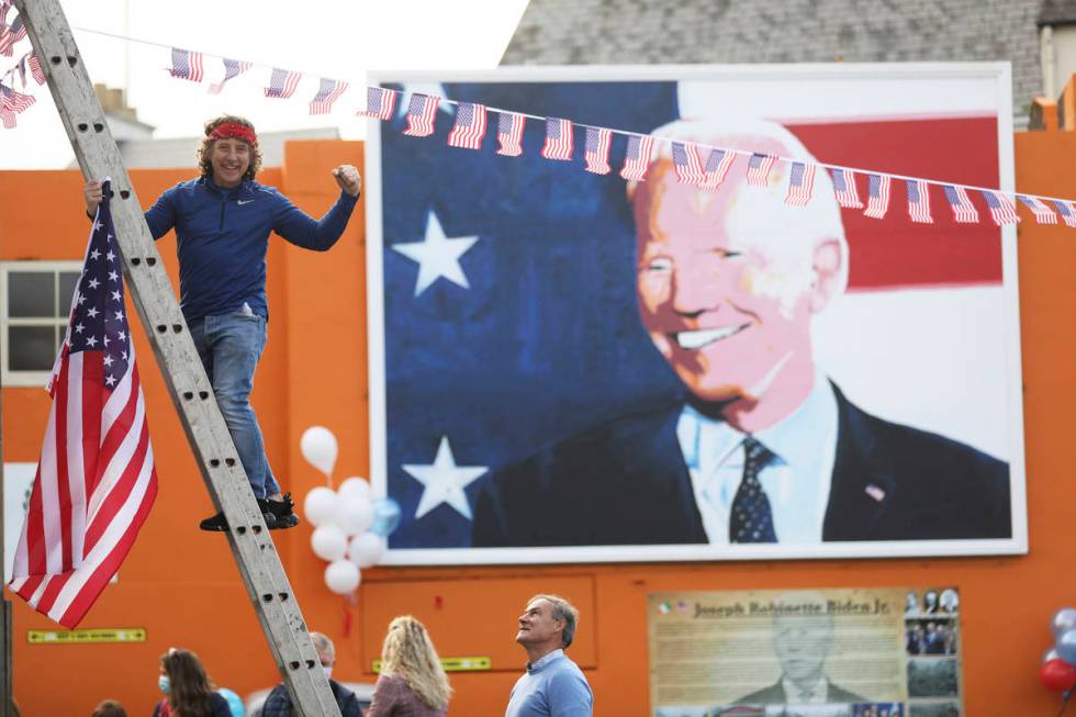 A man puts a US flag up in the town of Ballina, the ancestral home of President-elect Joe Biden ...