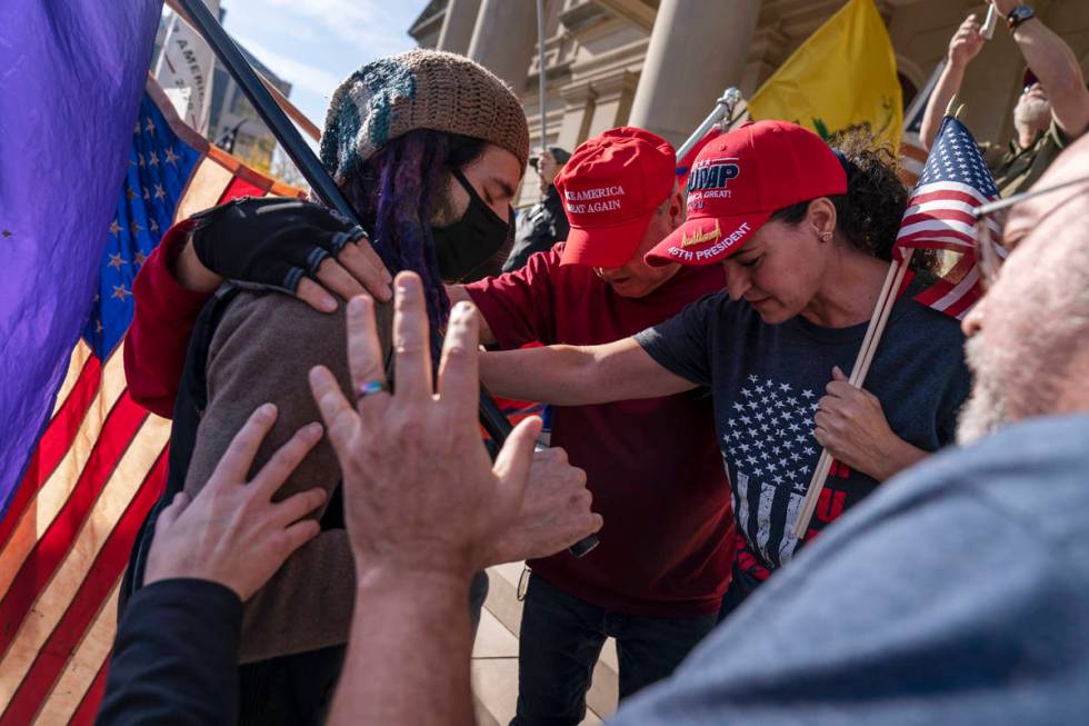 Trump supporters demonstrating during the election results, at right, pray with a counter prote ...