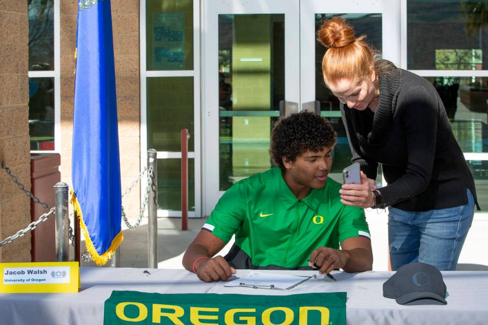 Jacob Walsh, who will play baseball for University of Oregon, looks at photos with his mother, ...