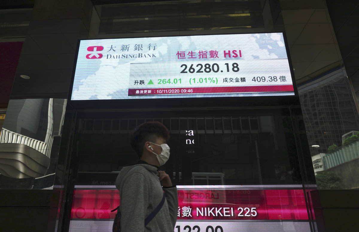 A man walks past a bank's electronic board showing the Hong Kong share index at Hong Kong Stock ...