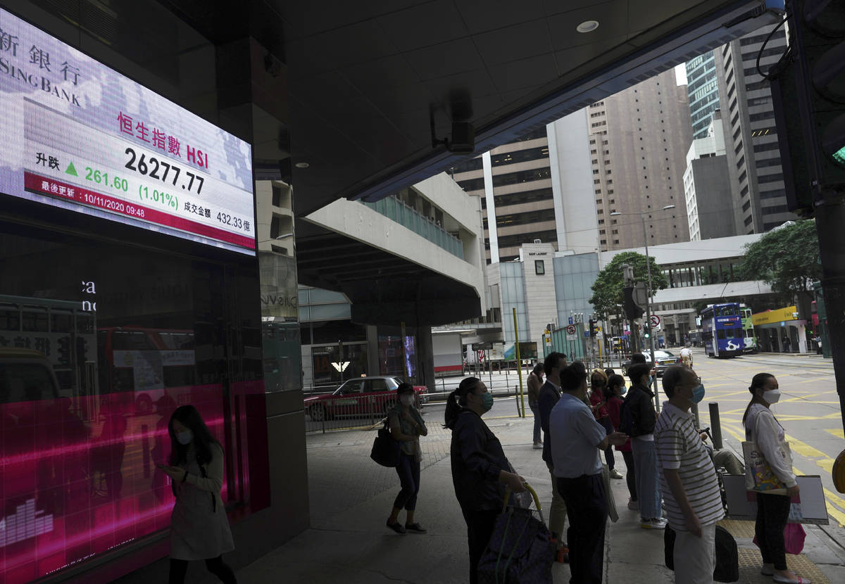 People stand near a bank's electronic board showing the Hong Kong share index at Hong Kong Stoc ...