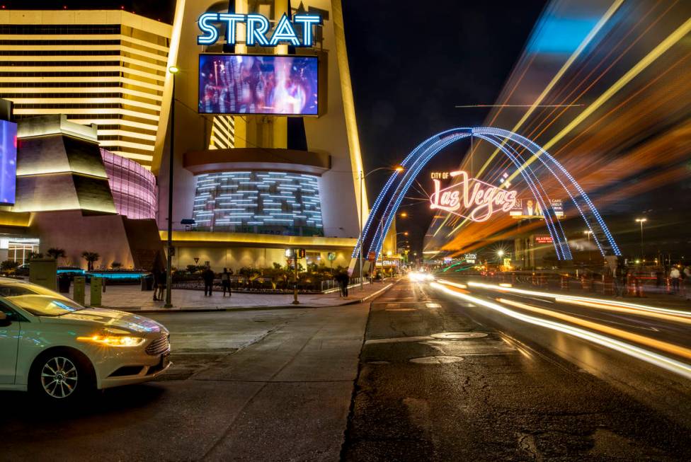 Cars stream down Las Vegas Boulevard past The Strat as the downtown gateway arches are fully il ...