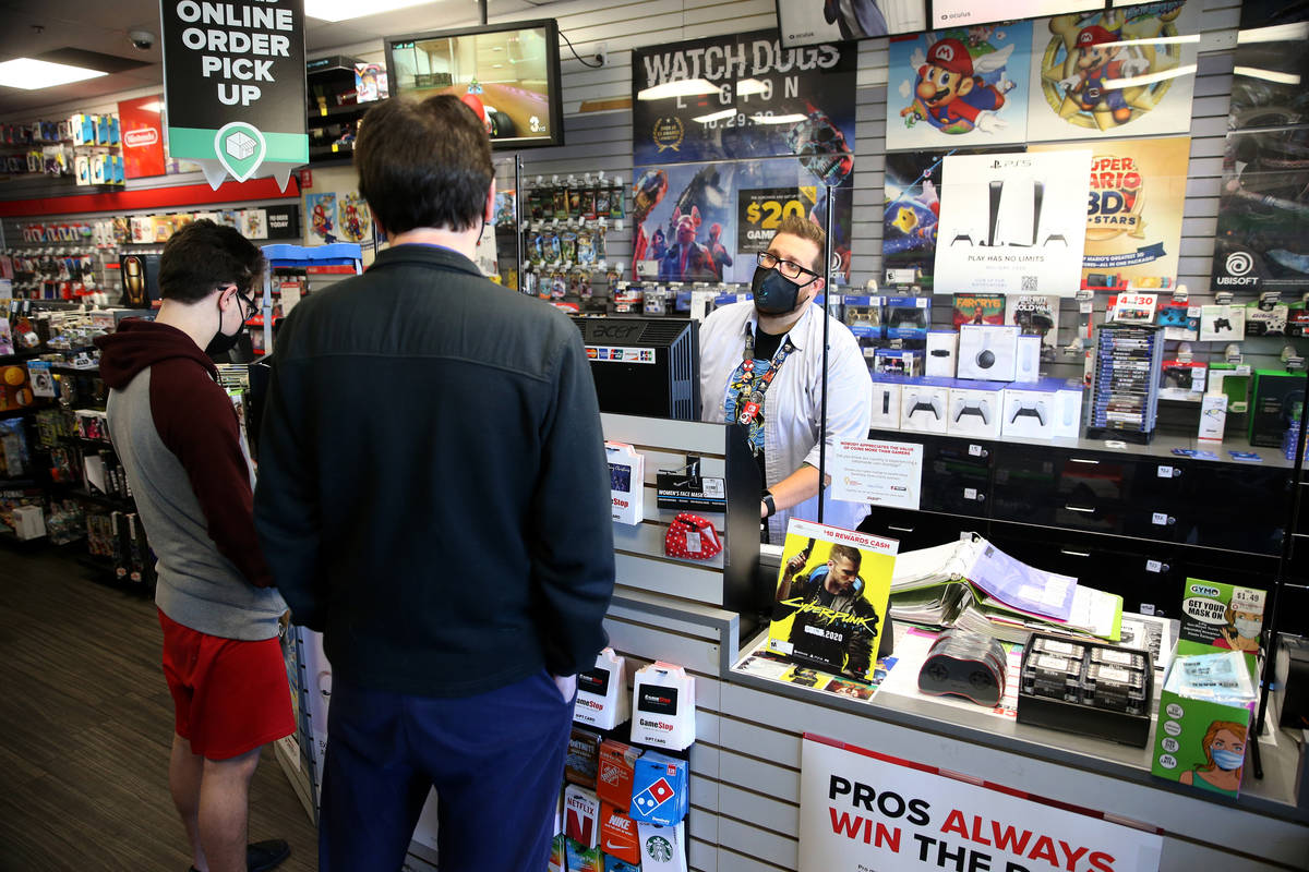 Assistant manager Eric Crosby, right, processes the Play Station 5 console order for a customer ...