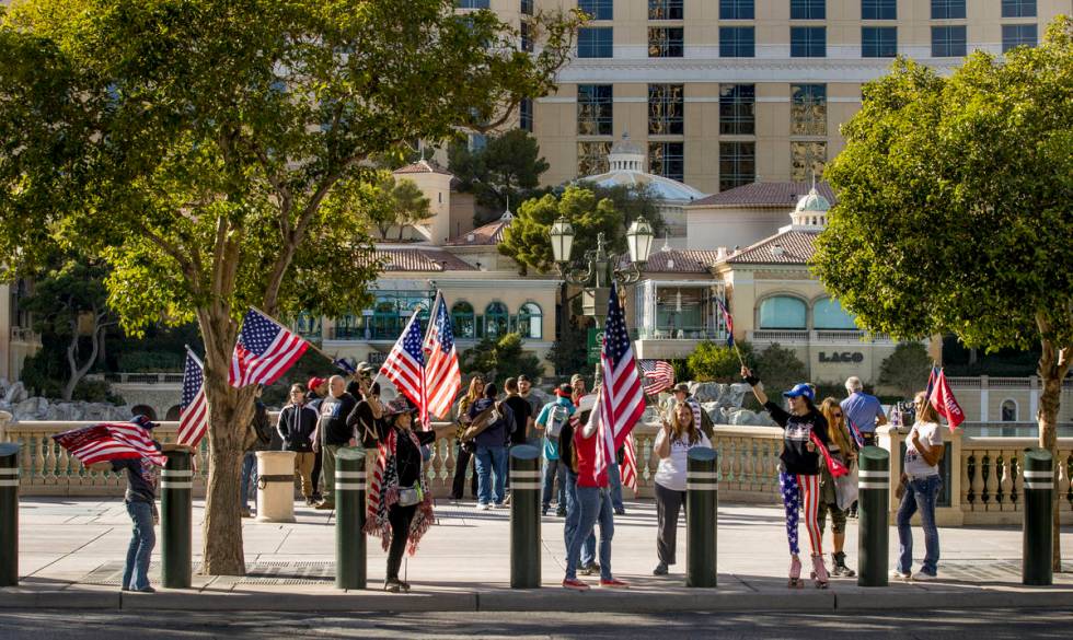 Flag wavers stop in front of the Bellagio during a Veterans Day march to peacefully protest Gov ...