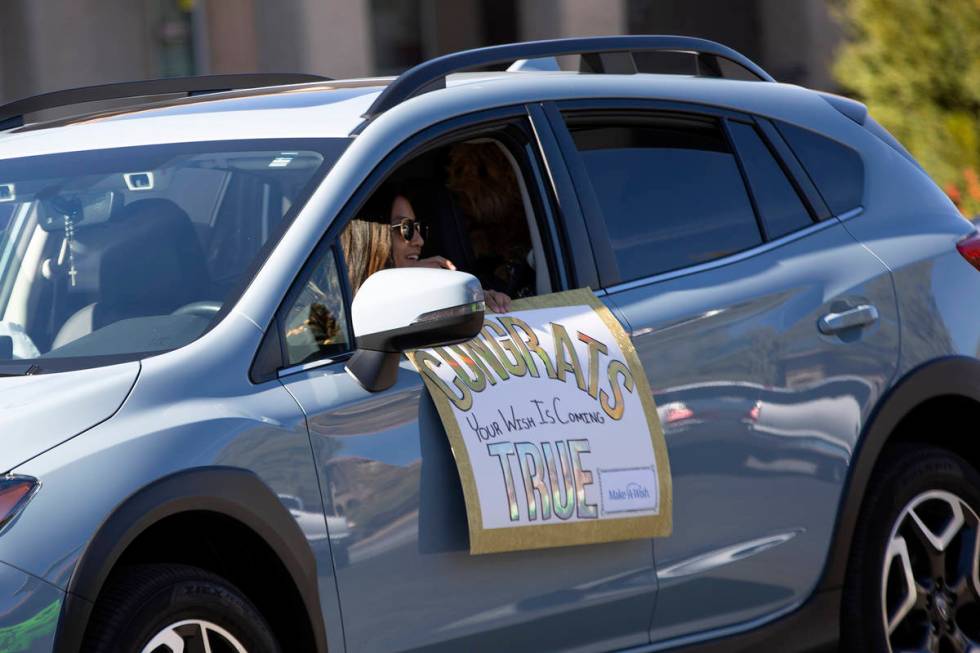 A car parade passes Las Vegan Lauren Cleveland, who received a new puppy from Make-A-Wish South ...