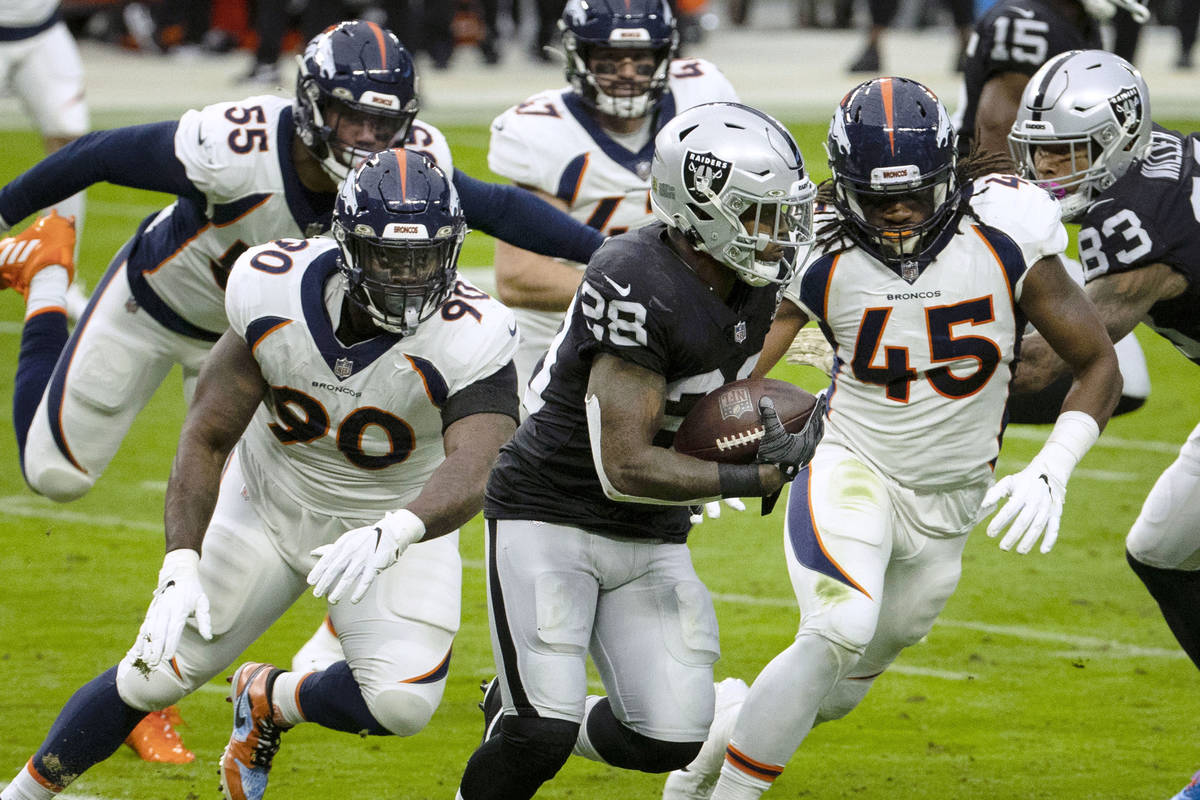 Las Vegas Raiders running back Josh Jacobs (28) chased by Denver Broncos players during the fir ...