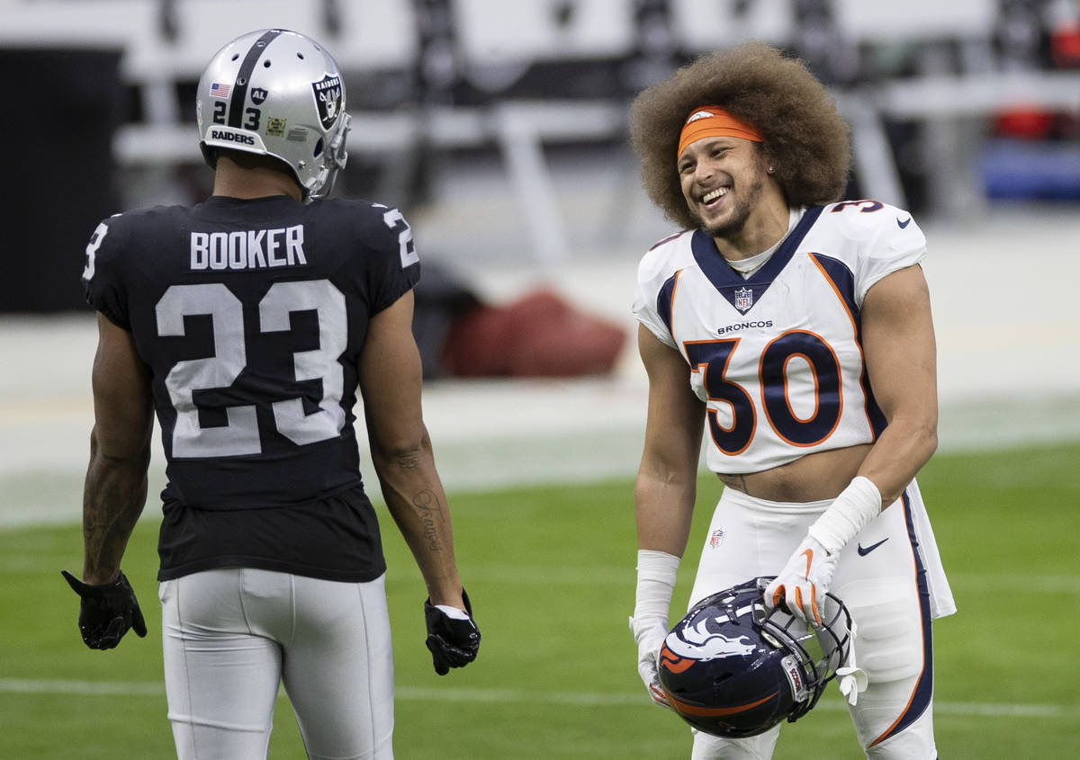 Denver Broncos running back Phillip Lindsay (30) shares a laugh with Las Vegas Raiders running ...