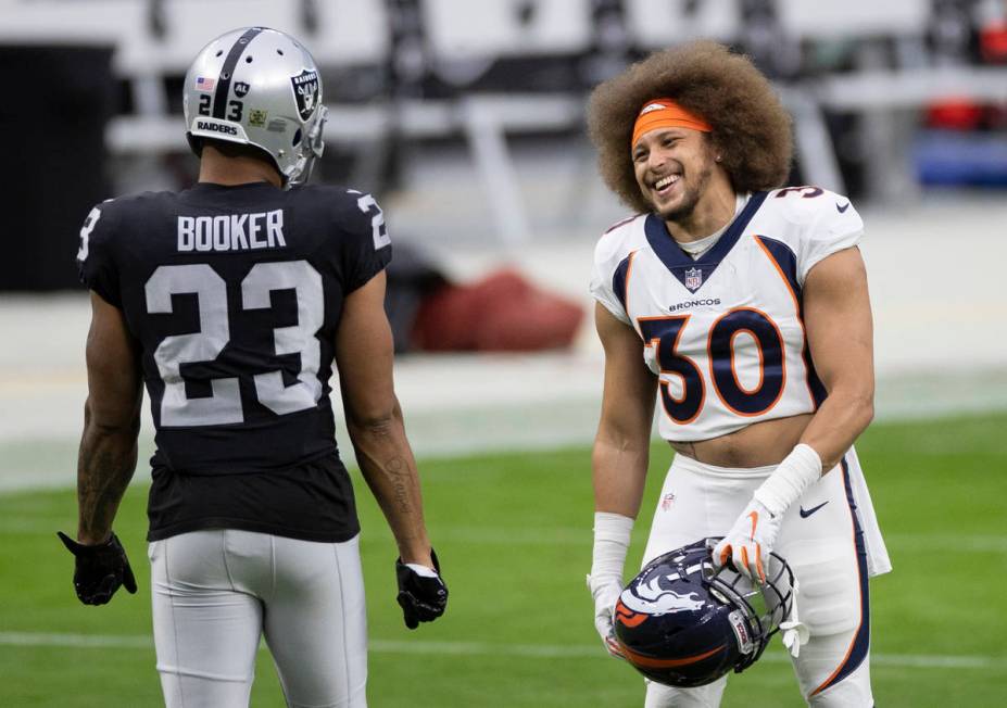 Denver Broncos running back Phillip Lindsay (30) shares a laugh with Las Vegas Raiders running ...