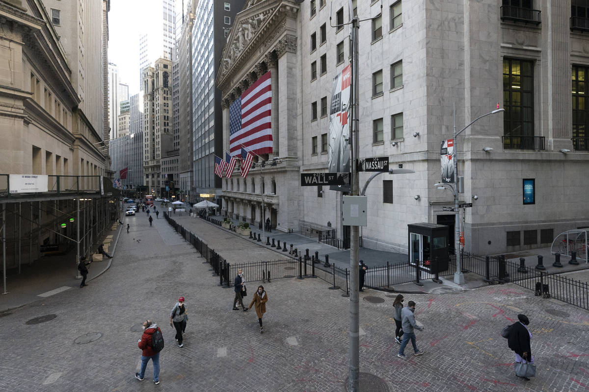 People walk by the New York Stock Exchange, Monday, Nov. 16, 2020, in New York. Stock markets a ...