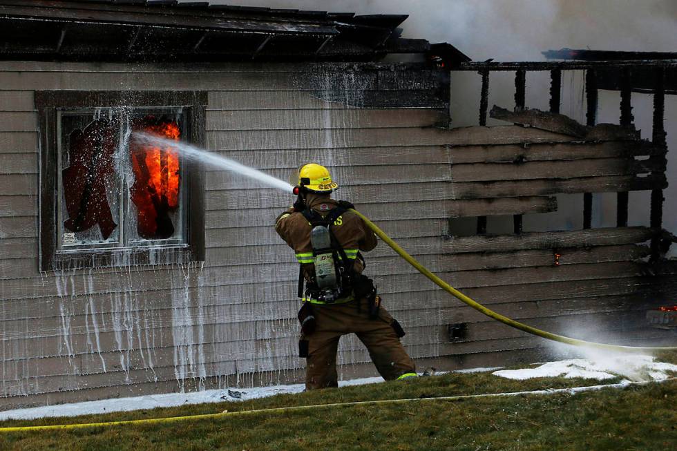 A firefighter tries to save a home during the Pinehaven Fire in the Caughlin Ranch area of Reno ...