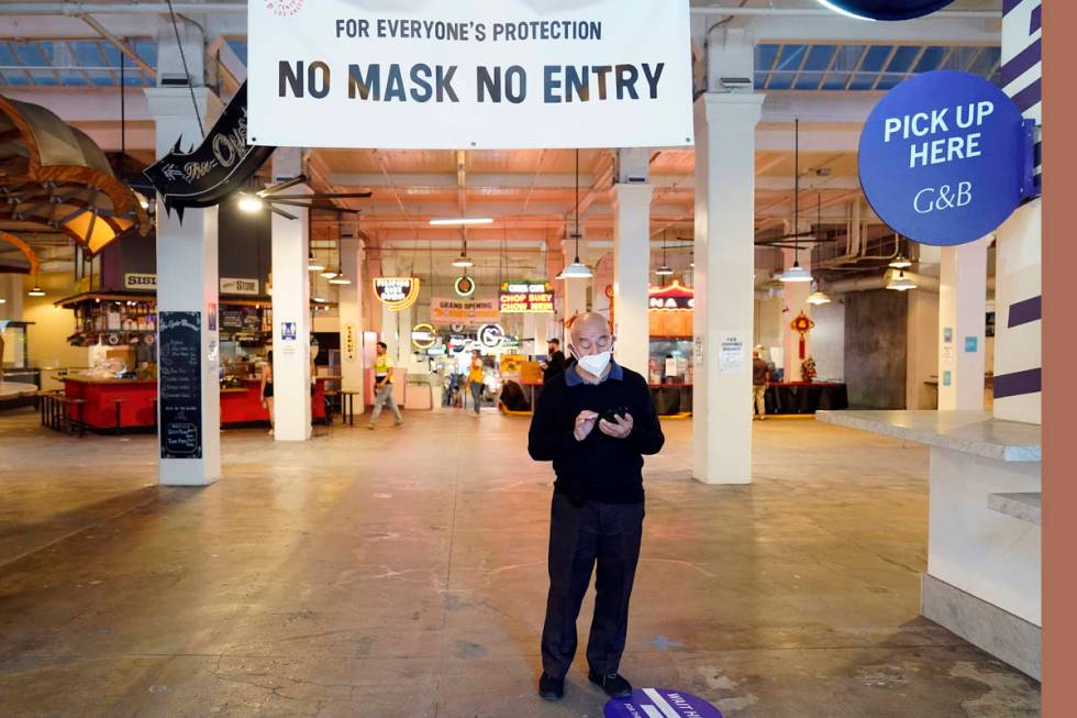 FILE - In this Nov. 16, 2020, file photo, a sign points to a mask mandate at the Grand Central ...