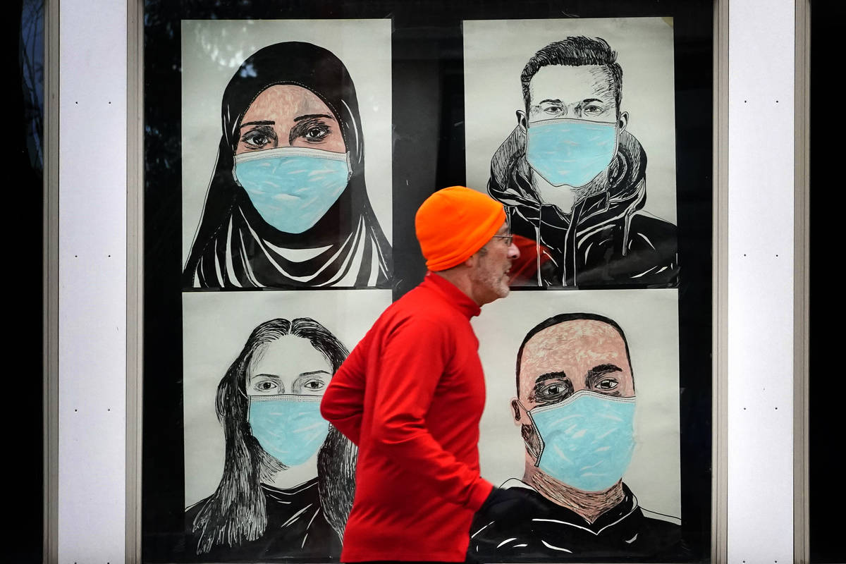 In this Nov. 16, 2020, file photo, a runner passes by a window displaying portraits of people w ...